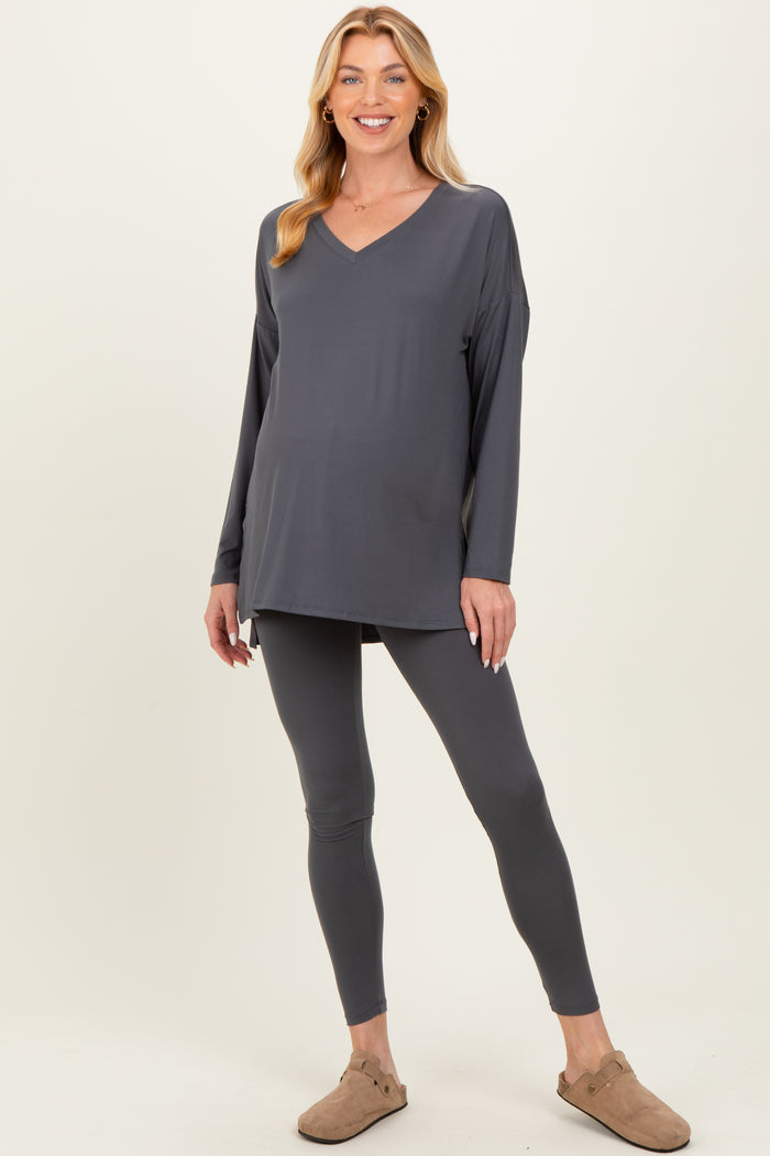 woman wearing a gray maternity top with a v-neck and matching leggings, showcasing her baby bump