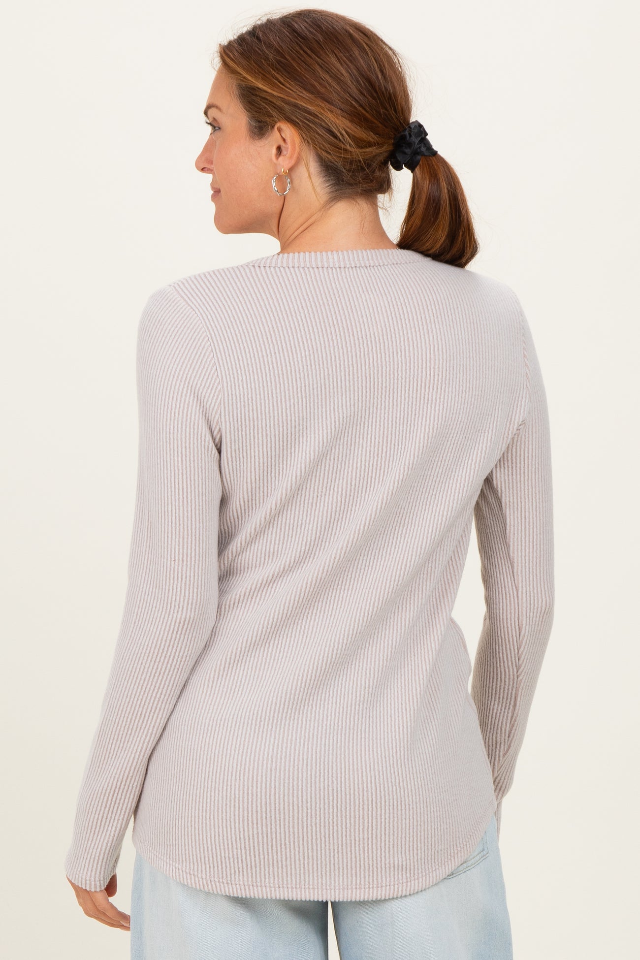 woman wearing a light gray ribbed long sleeve top, shown from the back with a relaxed fit