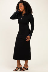 woman wearing a black long sleeve polo dress with a collar and denim detail on the cuffs, standing and smiling