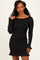 woman wearing a black ribbed long sleeve dress with ruffled hem details