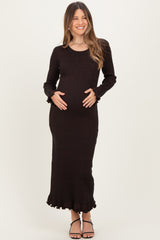 woman wearing a black long sleeve maternity dress with ruffled hem and holding her baby bump