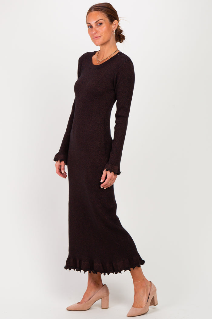 woman wearing a black long sleeve sweater dress with ruffled hem and a form-fitting silhouette
