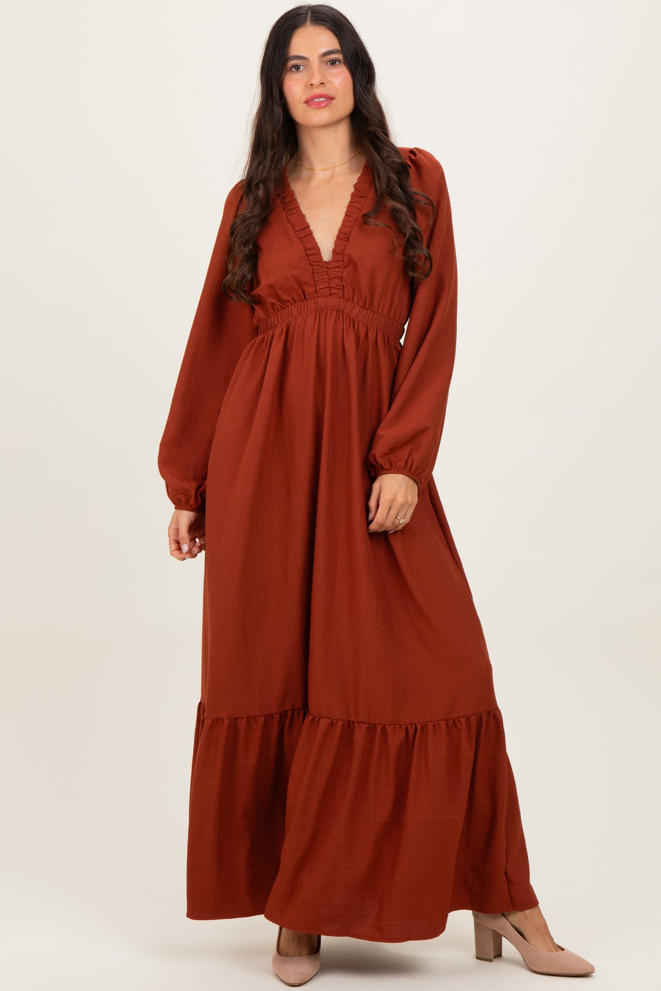 woman wearing an autumn rust long sleeve maxi dress with a deep v-neck and tiered hem