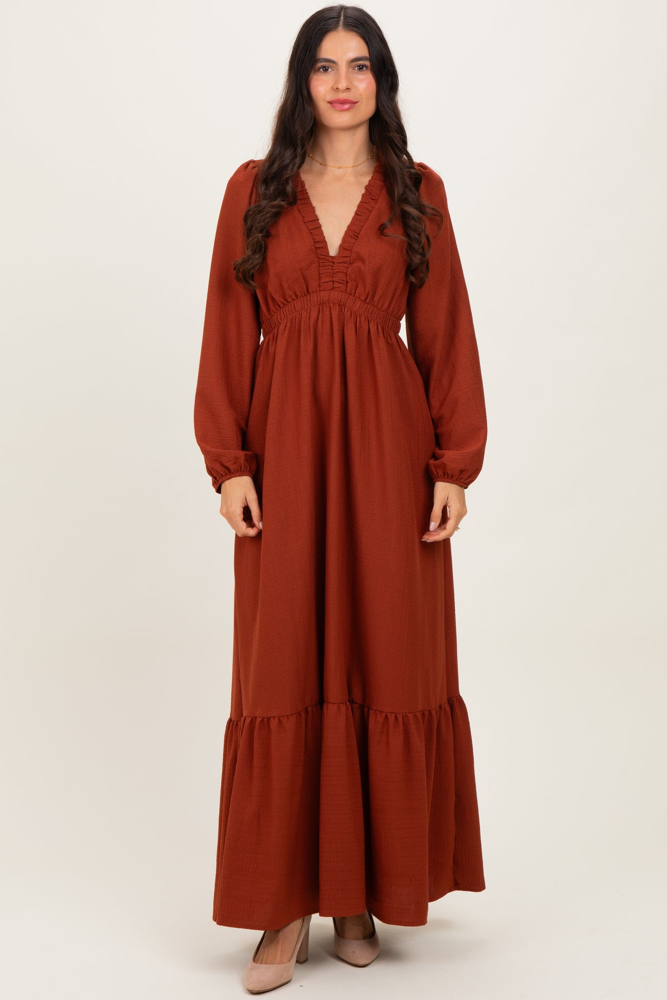 woman wearing a rust long sleeve maxi dress with a v-neck and ruffle details
