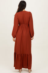 woman wearing a rust long sleeve maxi dress with puff sleeves and a tiered hem, viewed from the back