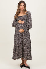 woman wearing a black floral maternity maxi dress and holding her baby bump