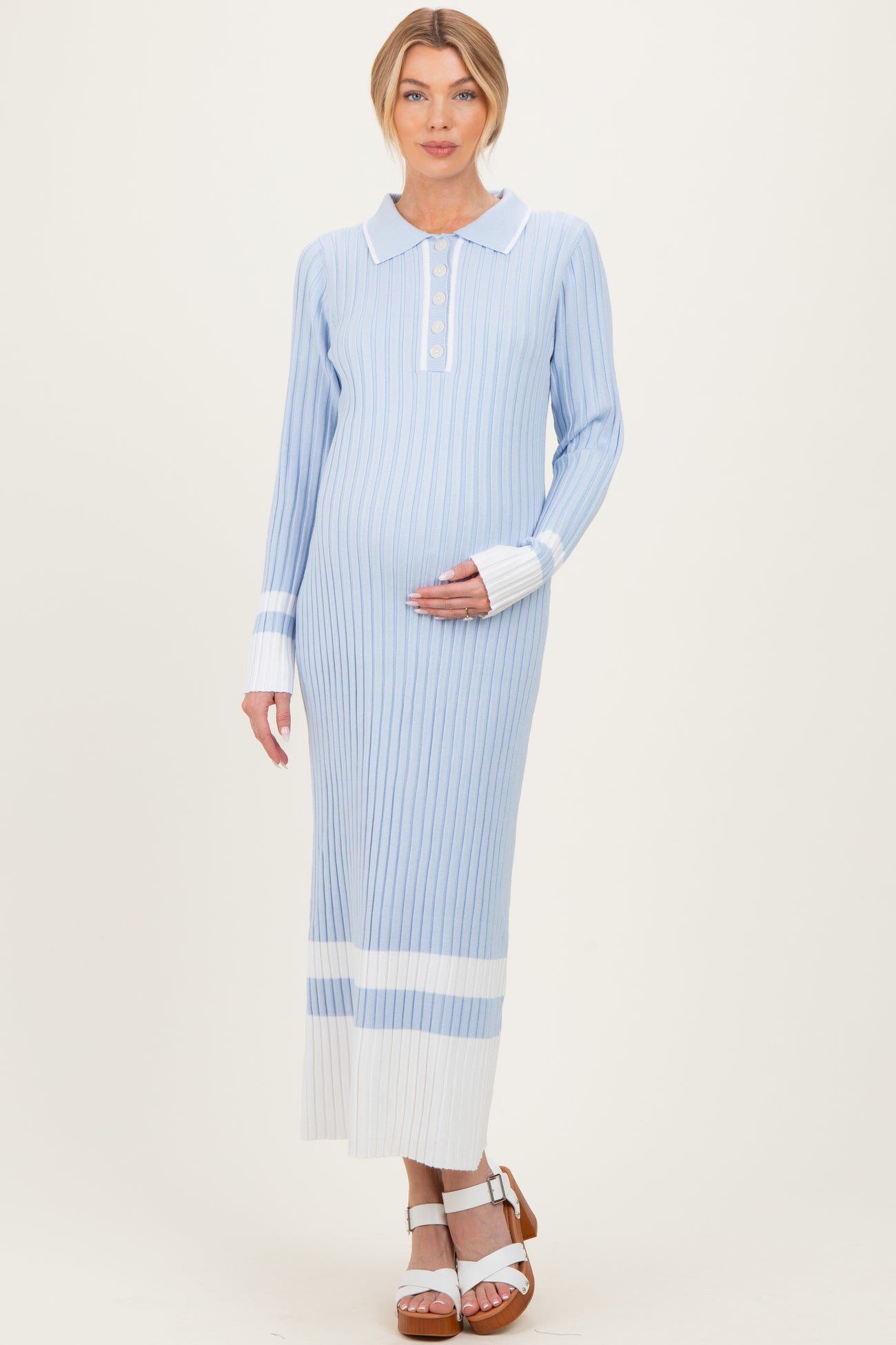 woman wearing a light blue striped maternity dress with a collar and button detail, holding her baby bump