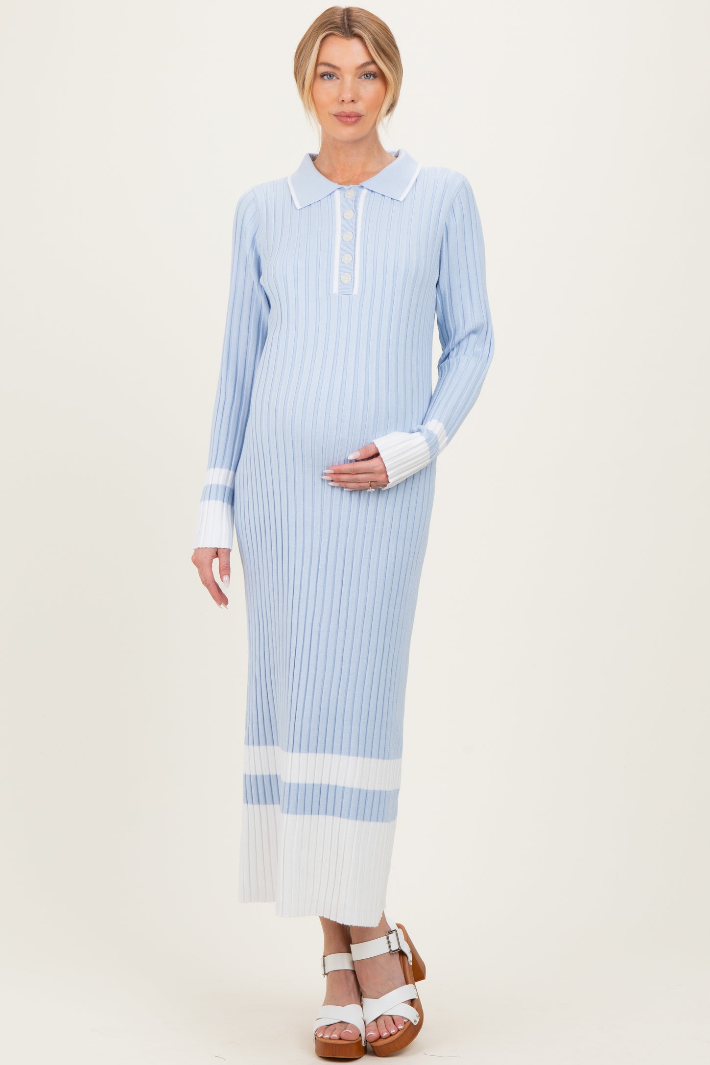 woman wearing a light blue striped maternity dress with a collar and button detail, holding her baby bump