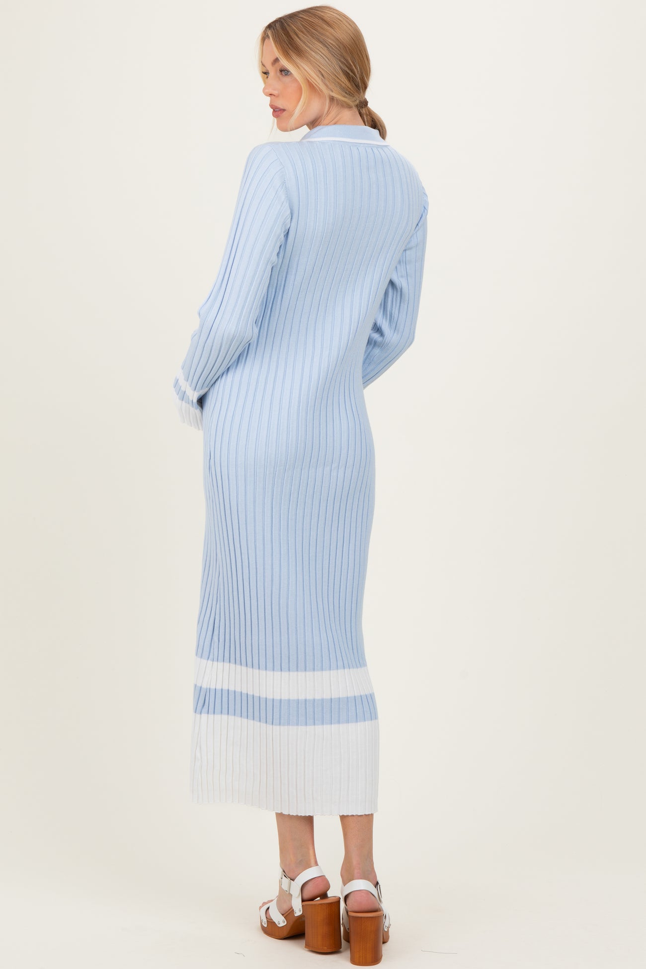 woman wearing a light blue ribbed maternity dress with white stripes on the hem, showing a fitted silhouette from the back