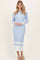 woman wearing a light blue ribbed midi dress with long sleeves and button details at the neckline
