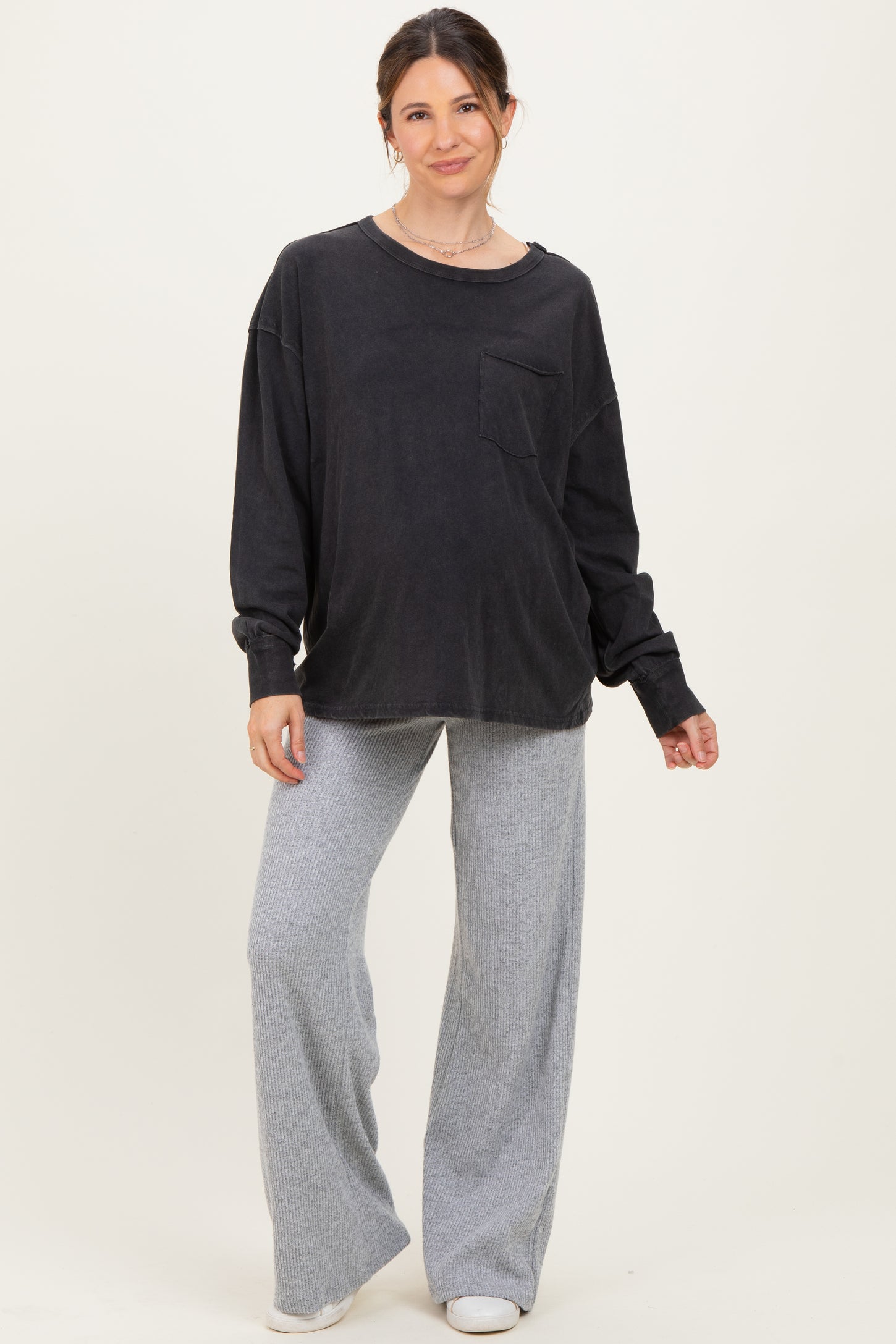 woman wearing a black long sleeve oversized maternity top with a pocket and gray wide-leg maternity pants