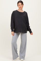 woman wearing a black long sleeve oversized maternity top with a pocket and gray wide-leg maternity pants