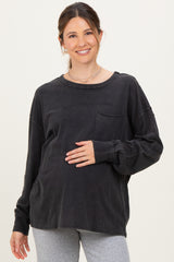 woman wearing a black oversized long sleeve maternity top and holding her baby bump
