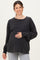 woman wearing a black oversized long sleeve maternity top and holding her baby bump