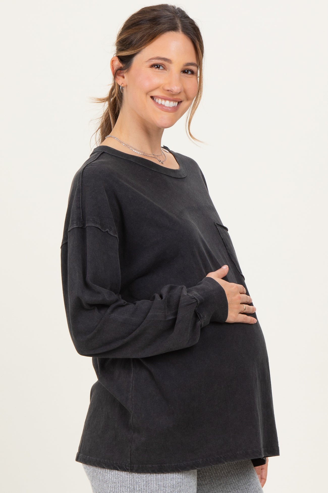 woman wearing a black long sleeve maternity top and holding her baby bump