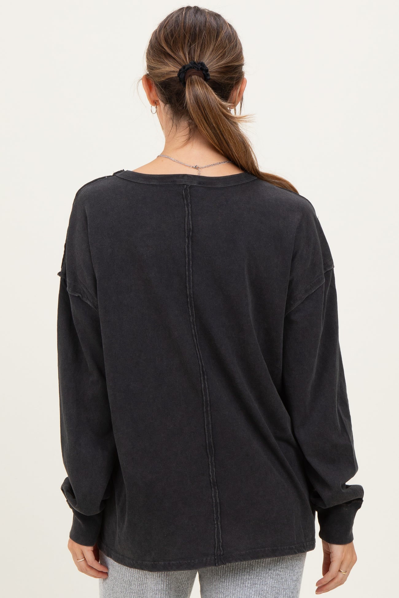 woman wearing a black long sleeve oversized maternity top with a relaxed fit, seen from the back
