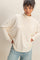 woman wearing a cream oversized turtleneck sweater with relaxed fit and light blue jeans