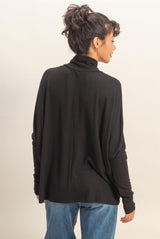 woman wearing a black turtleneck sweater with a relaxed fit and long sleeves, seen from the back
