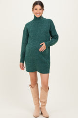 woman wearing a green turtleneck maternity sweater dress and holding her baby bump