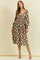 woman wearing a brown floral midi dress with long sleeves and a loose fit, standing against a beige background