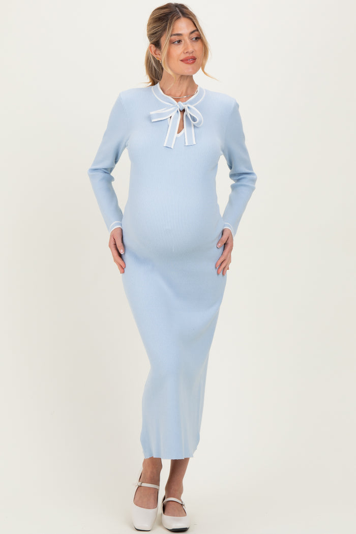 woman wearing a light blue ribbed maternity dress with long sleeves and a bow tie detail, showing her baby bump