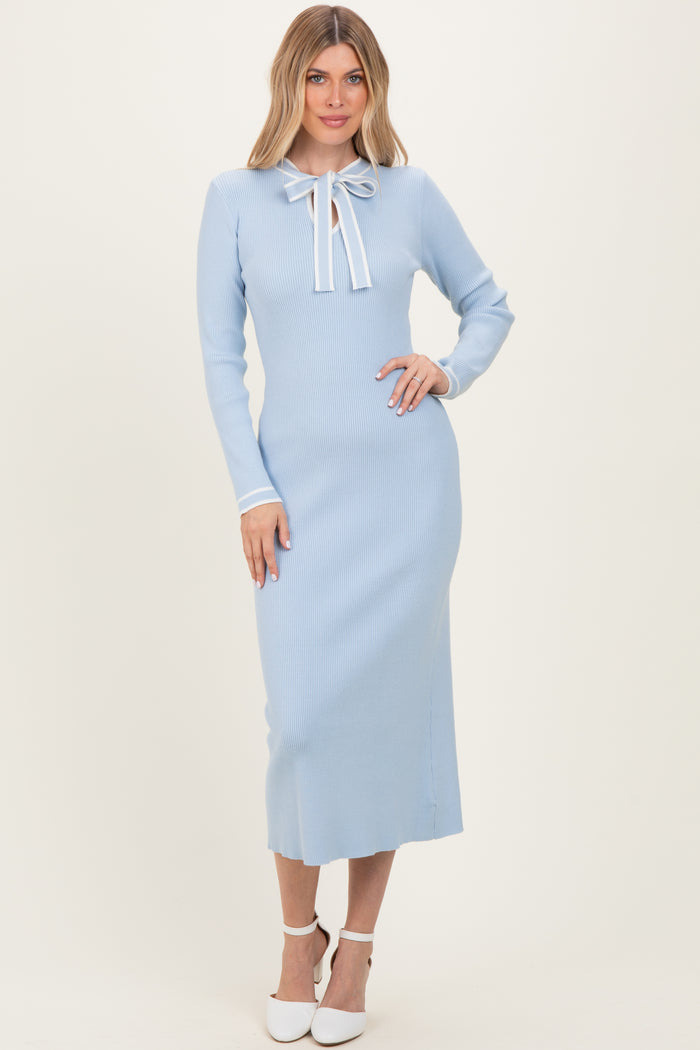woman wearing a baby blue ribbed midi dress with long sleeves and a bow tie neck detail