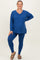 woman wearing a vibrant blue long sleeve maternity top and matching leggings, posing with one hand on her hip, showcasing her baby bump
