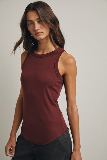 woman wearing a burgundy sleeveless top with a round neckline and a slight high-low hem