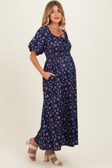 woman wearing a navy blue floral maternity maxi dress with puff sleeves and a baby bump visible