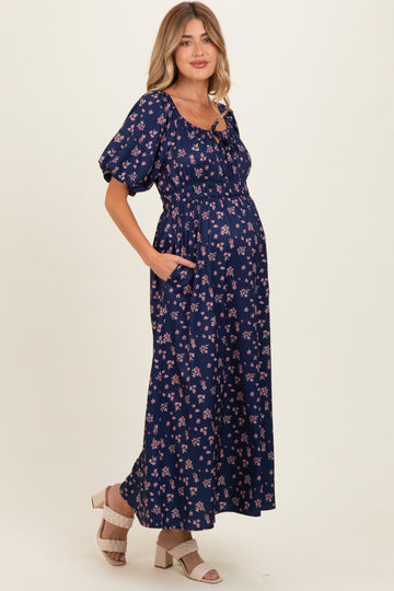 woman wearing a navy blue floral maternity maxi dress with puff sleeves and a baby bump visible