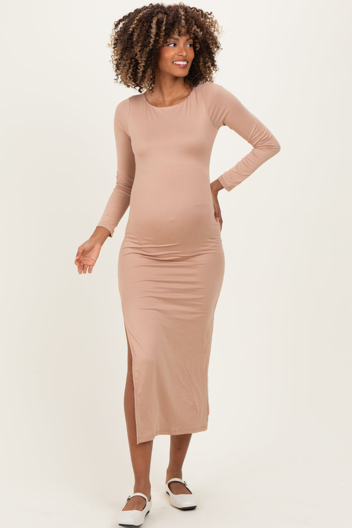 woman wearing a beige long sleeve maternity dress with a side slit and visibly holding her baby bump