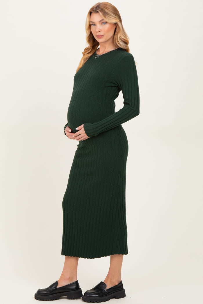 woman wearing a dark green ribbed long sleeve maternity dress and cradling her baby bump