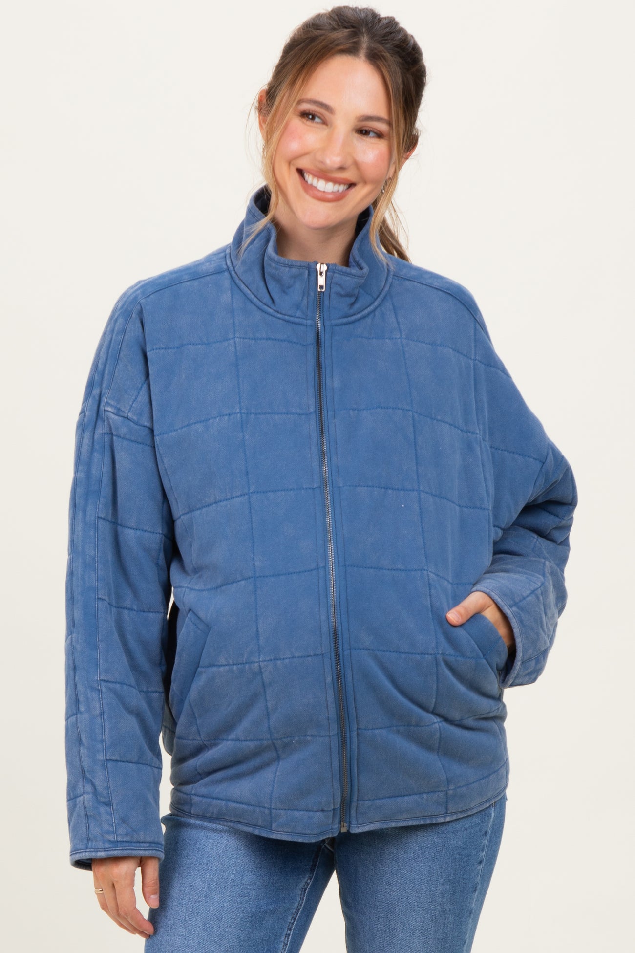 woman wearing a blue quilted maternity jacket with a high collar and side pockets