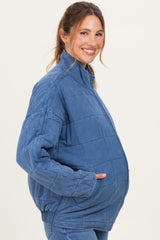 woman wearing a blue quilted maternity jacket with a relaxed fit and side pockets, showcasing her baby bump
