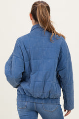 woman wearing a blue quilted maternity jacket with a cinched waist, viewed from the back