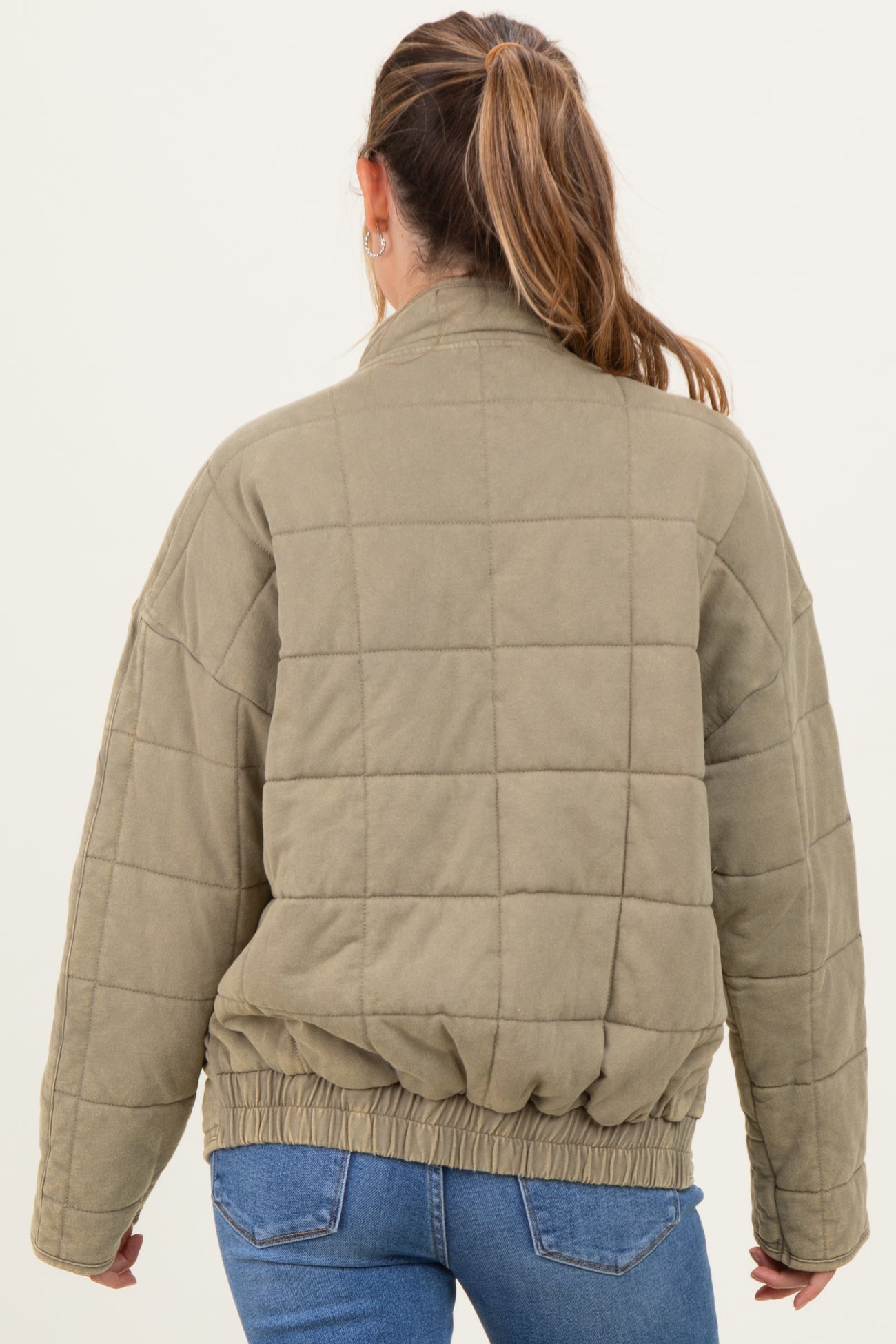 woman wearing a green quilted maternity jacket with a cinched hem, viewed from the back