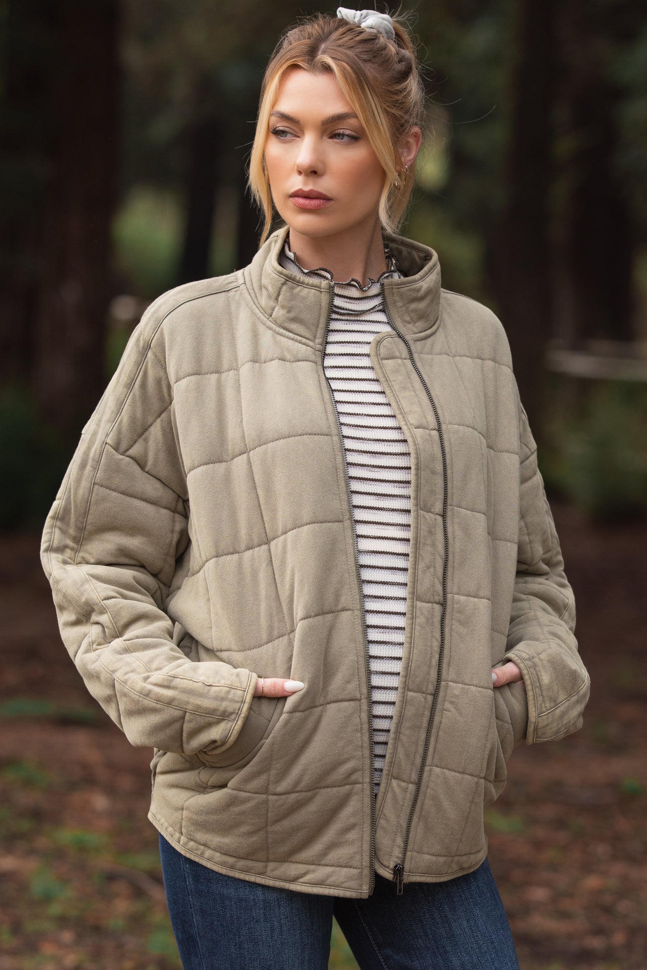 woman wearing a light beige quilted maternity jacket over a striped top, standing outdoors with hands in pockets
