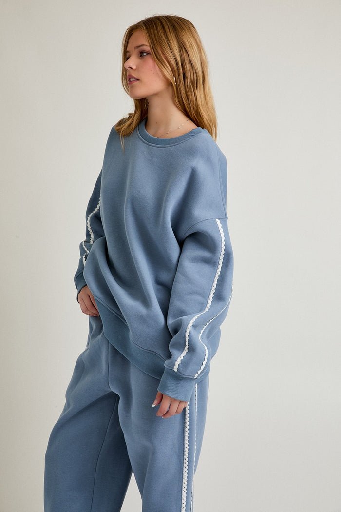 woman wearing a light blue oversized sweatshirt with white side detailing and matching sweatpants