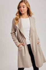 woman wearing a beige long cardigan with open front and pockets over a white top and black pants
