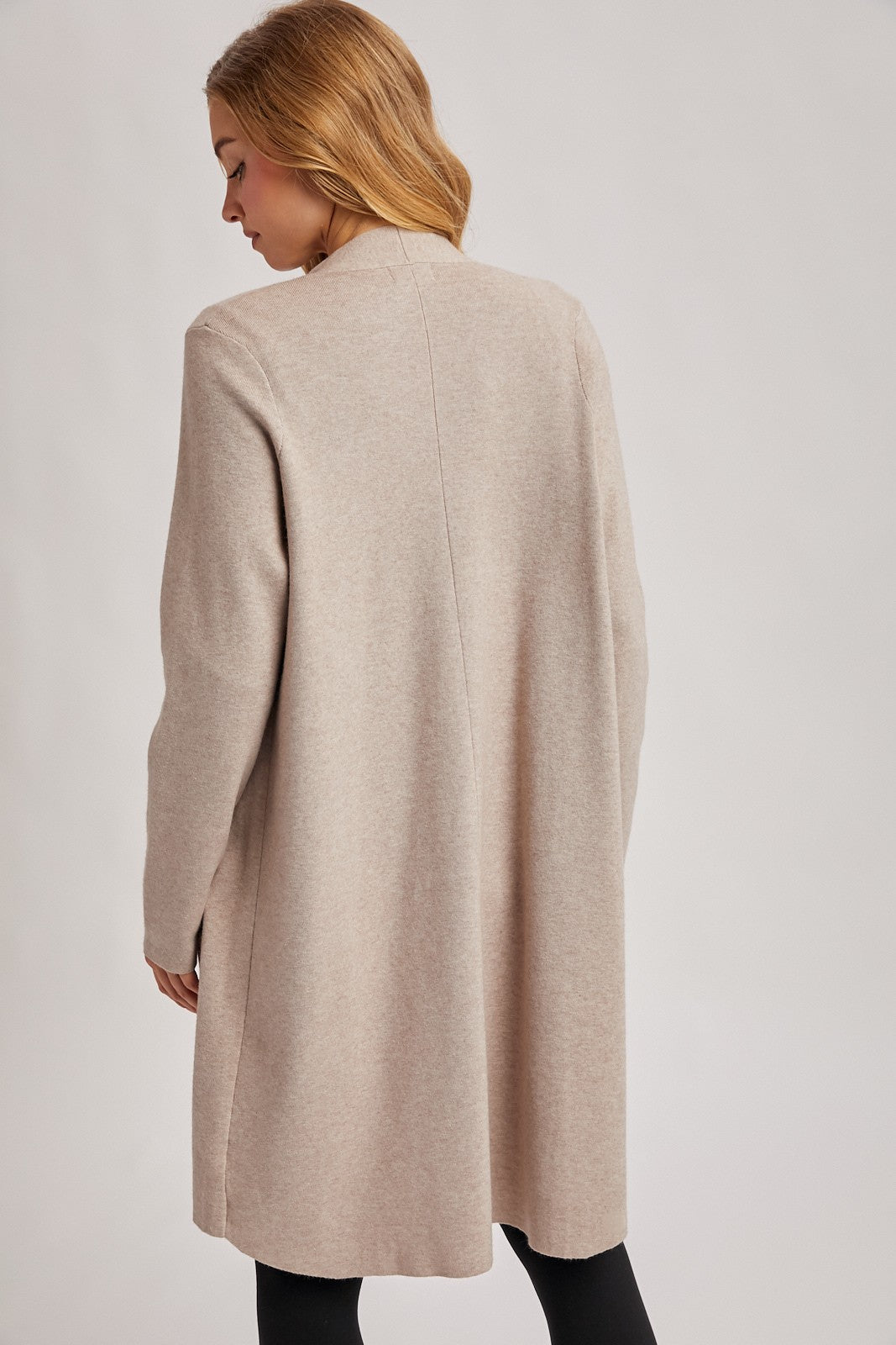 woman wearing a beige longline cardigan with a relaxed fit, seen from the back