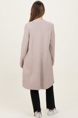 woman wearing a light pink maternity coat, seen from the back, paired with black pants and white sneakers