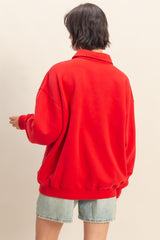 woman wearing a red oversized sweatshirt with a collar, paired with denim shorts, viewed from the back