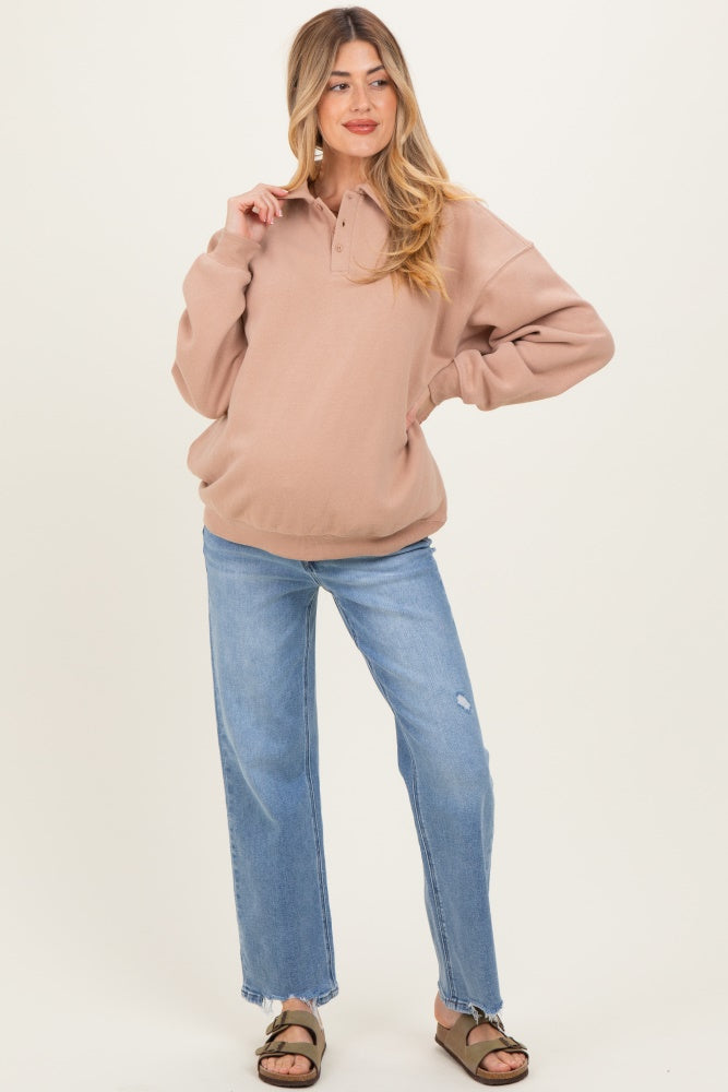 woman wearing a beige maternity pullover sweater and light blue distressed straight leg jeans with a visible baby bump