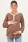 woman wearing a brown ribbed maternity top with button details and holding her baby bump