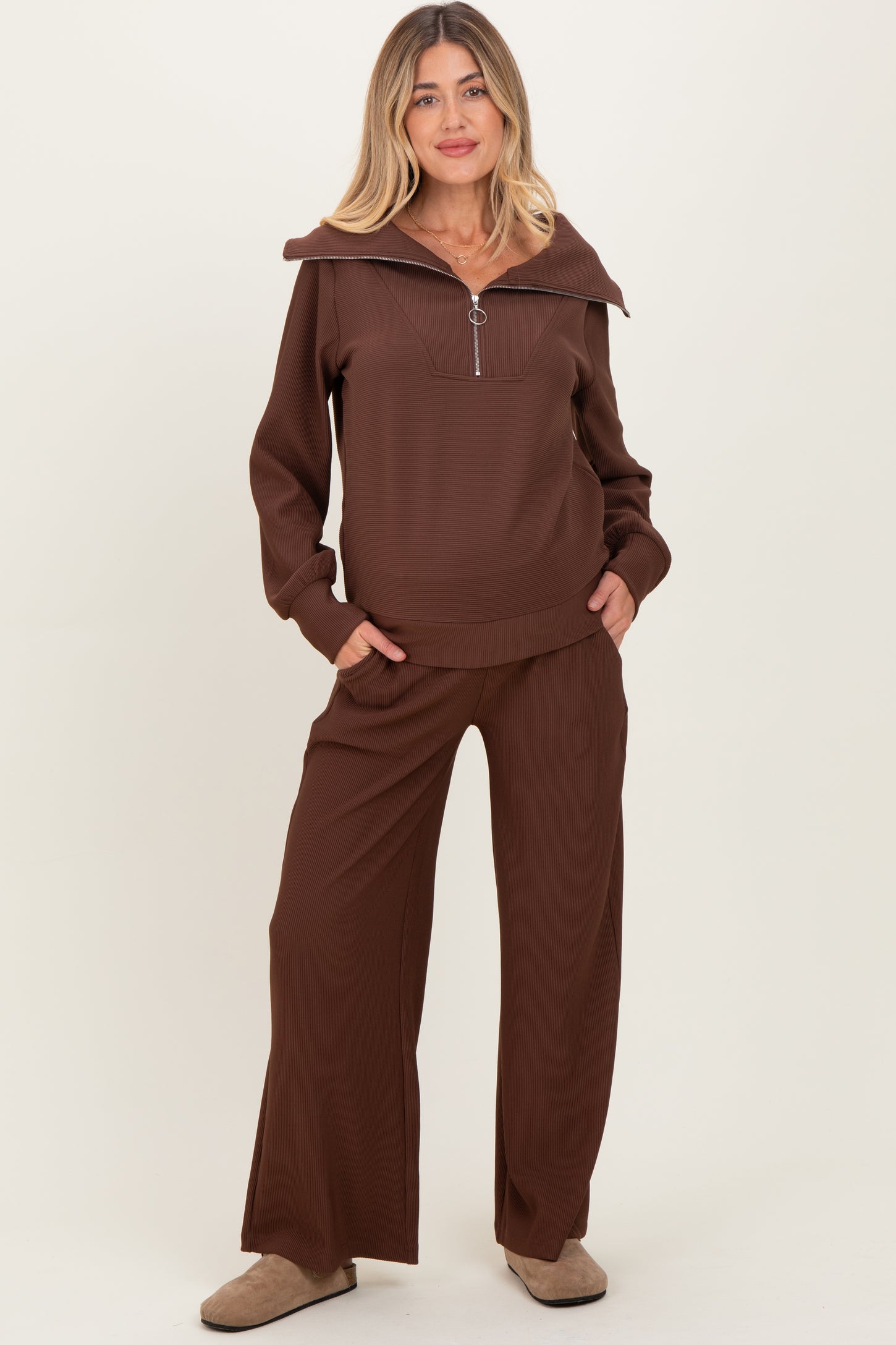 woman wearing a brown maternity loungewear set with a zip-up top and wide-leg pants, featuring a relaxed fit