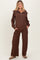 woman wearing a brown maternity loungewear set with a zip-up top and wide-leg pants, featuring a relaxed fit