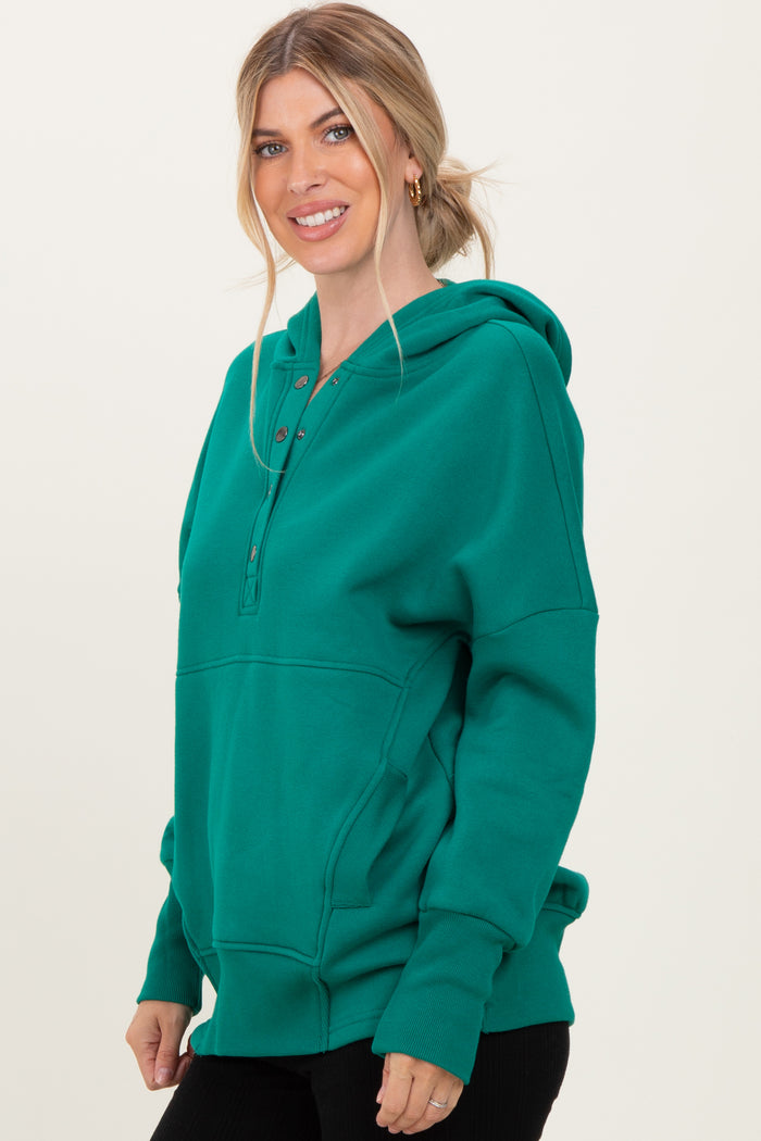 woman wearing a green hooded sweatshirt with a button-up neckline and a front pocket
