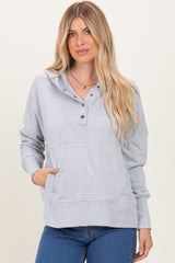 woman wearing a light grey pullover hoodie with buttons and a front pocket, paired with blue jeans