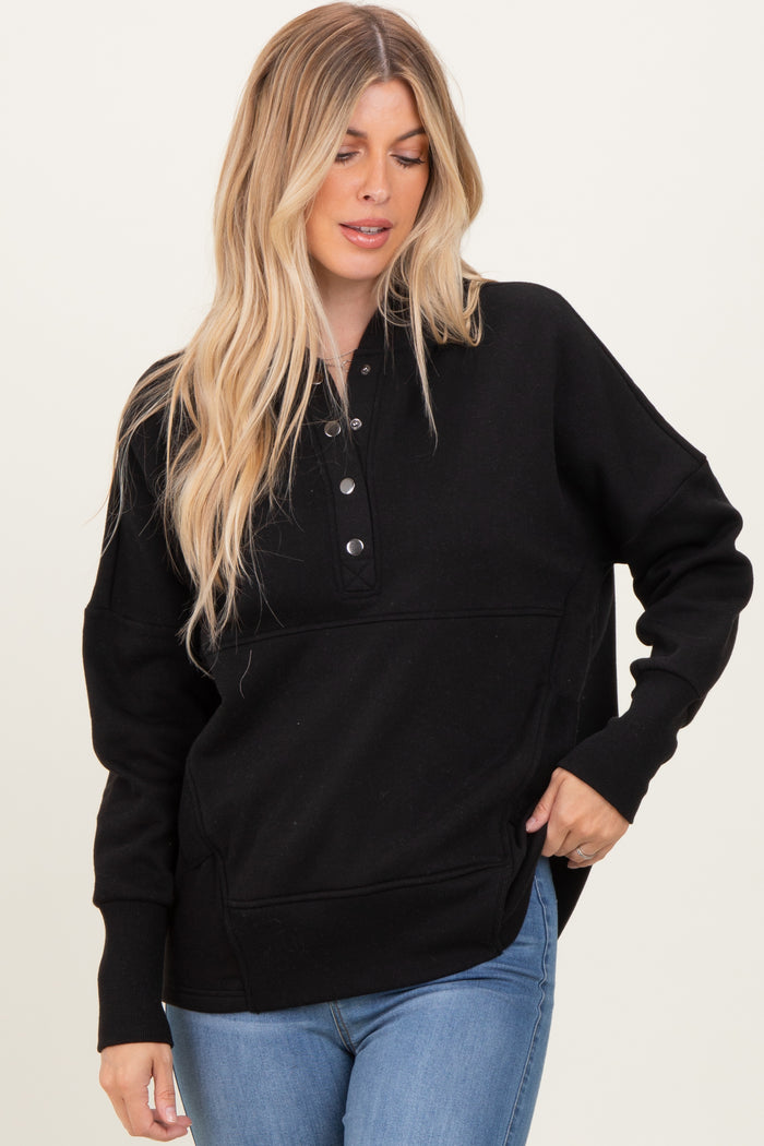 woman wearing a black long sleeve oversized pullover with button details and side pockets