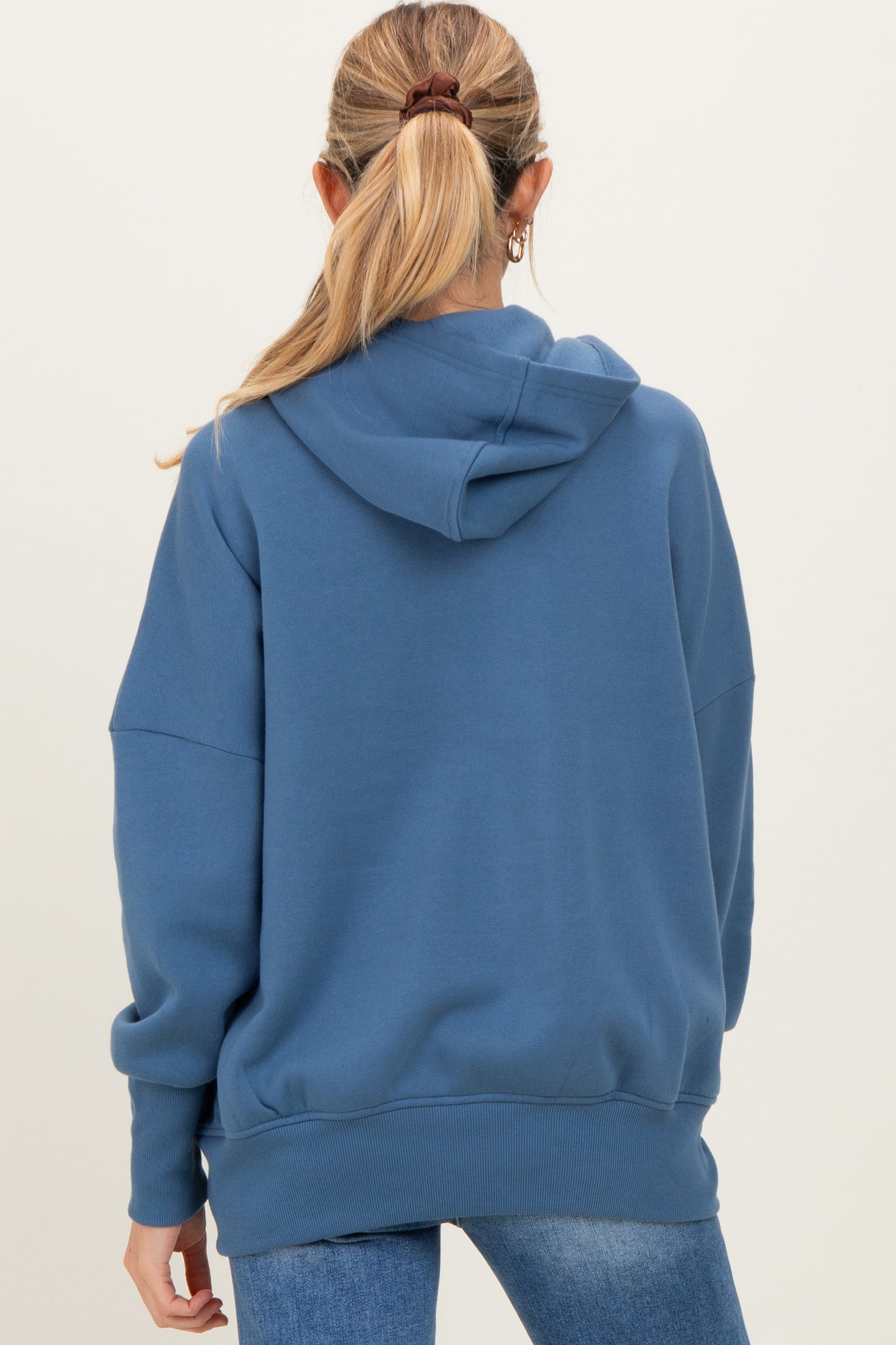 woman wearing a blue oversized maternity hoodie, seen from the back, with a hood and long sleeves